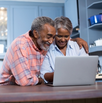 Smiling elderly couple pleased with something they're seeing on their laptop