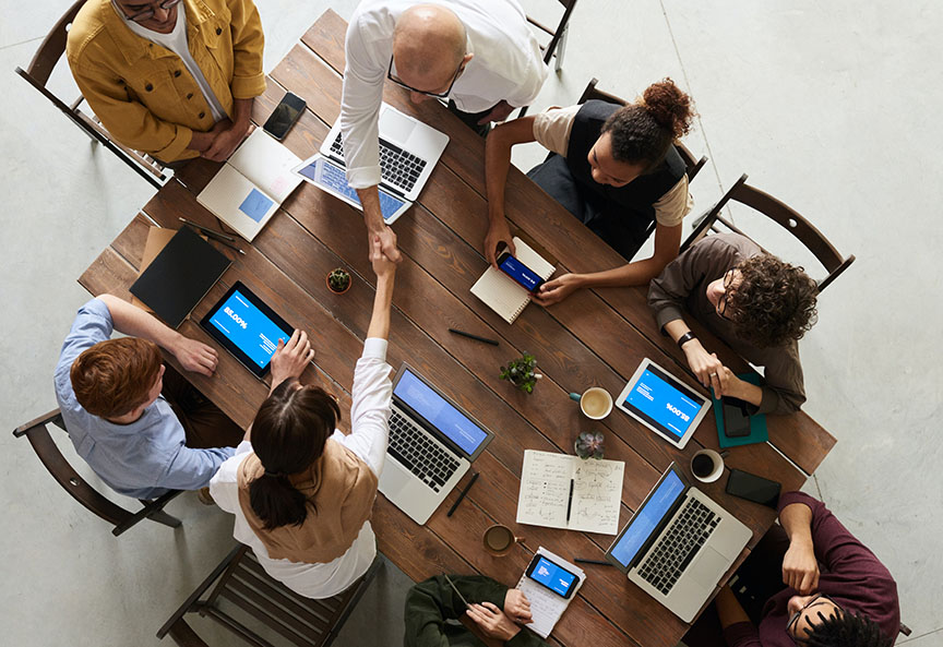 Birds-eye perspective of business team working at a table with their laptops and tablets